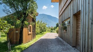 A gravel driveway leading to a wooden building with a mountain in the background.