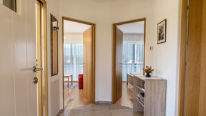 A hallway with wooden doors, a mirror, a red chair, and a wooden cabinet with a vase.
