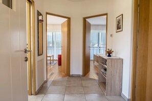 A hallway with wooden doors, a mirror, a red chair, and a wooden cabinet with a vase.