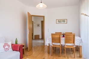 Une pièce comprenant un lit, une table à manger avec des chaises, une porte en bois et un luminaire suspendu.