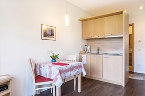 Eine kleine Küche mit Holdekor-Schränken, einem Esstisch mit einem roten Stuhl und einem gerahmten Bild an der Wand.