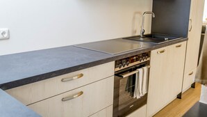 Eine moderne Küche mit einer Edelstahl-Dunstabzugshaube, einem Doppelbackofen und hellen Holzschränken.