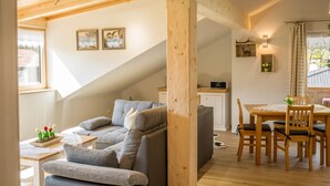 Ein gemütlicher Wohnbereich mit einer Couch, einem Esstisch mit Stühlen, einer Treppe und einer Küchenzeile.