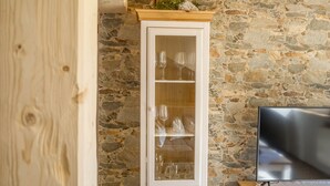 Eine Steinsäule, ein Holzschrank mit Glastüren und ein Flachbildfernseher.