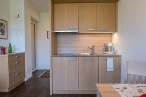 Une cuisine de taille réduite, avec des meubles de rangement en bois, une cuisinière encastrée et un évier.
