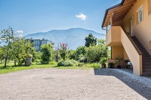 Un bâtiment avec un escalier, une allée en terre battue et une montagne en arrière-plan.