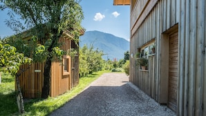 Un chemin de gravier mène à un bâtiment en bois, avec une montagne en arrière-plan.