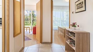 Un couloir avec des portes en bois donnant sur une salle à manger et un salon doté d’une fenêtre.