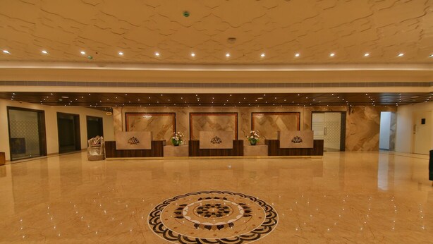 A spacious lobby with a polished marble floor, a central decorative pattern, and a reception desk with a logo. - Accord Chrome (Chennai)