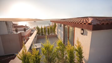Enjoy breathtaking views of the water from this balcony with a table and chairs.