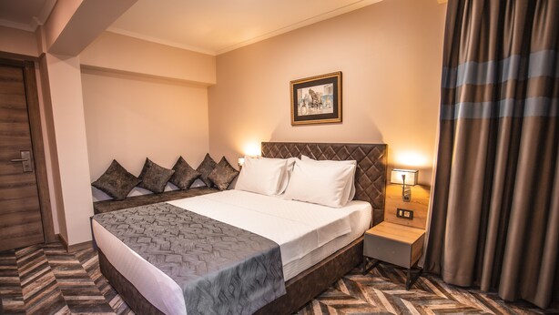 A hotel room with a large bed, a nightstand, a wall-mounted lamp, and a framed picture. - Hotel Kale 17 (Çanakkale)