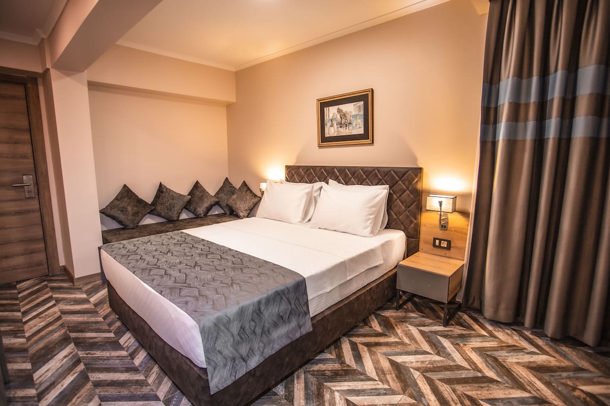 Habitación de hotel con una cama grande, una mesita de noche, una lámpara de pared y un cuadro enmarcado.