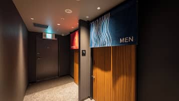 A hallway with a men's restroom sign, a door with a digital display, and a carpeted floor.