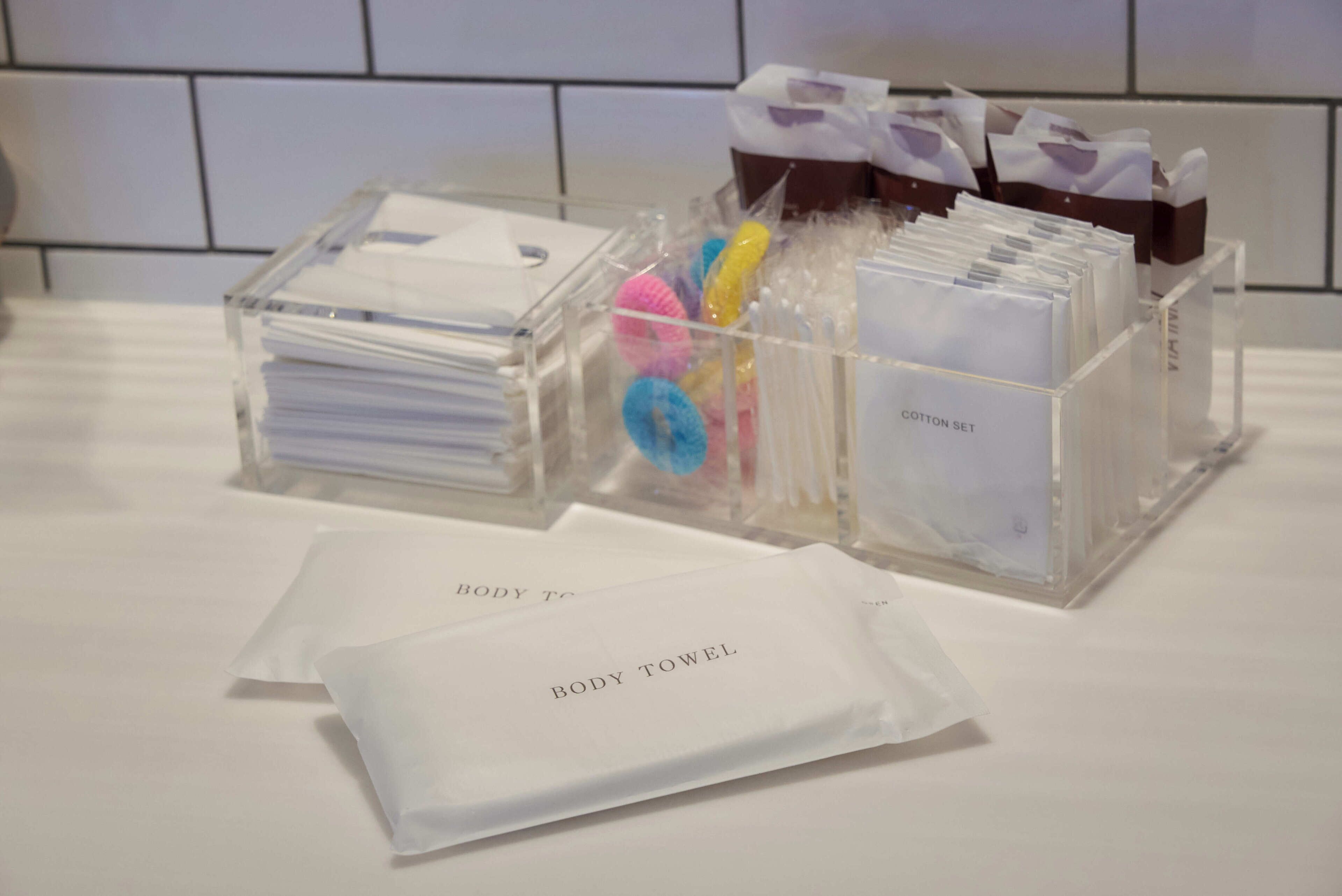 A hotel reception area with clear plastic storage boxes containing various items like towels and toiletries.