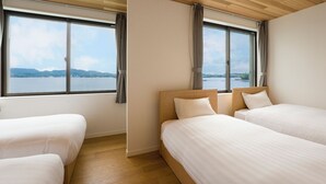 Une chambre dâhĂŽtel avec deux lits, une grande fenĂȘtre avec des rideaux et une vue sur un lac et des montagnes.