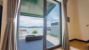 Une chambre moderne dotĂ©e dâune porte-fenĂȘtre coulissante donnant sur un balcon Ă©quipĂ© dâun foyer et de chaises longues.