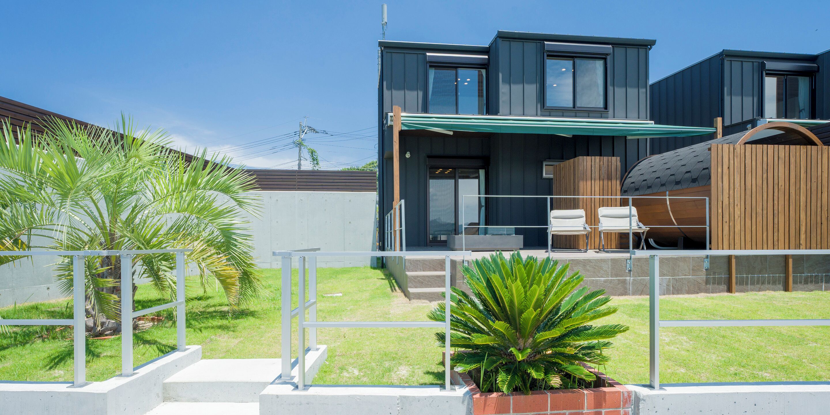 Uma casa moderna de dois andares com varanda coberta, quintal cercado e um pequeno jardim.