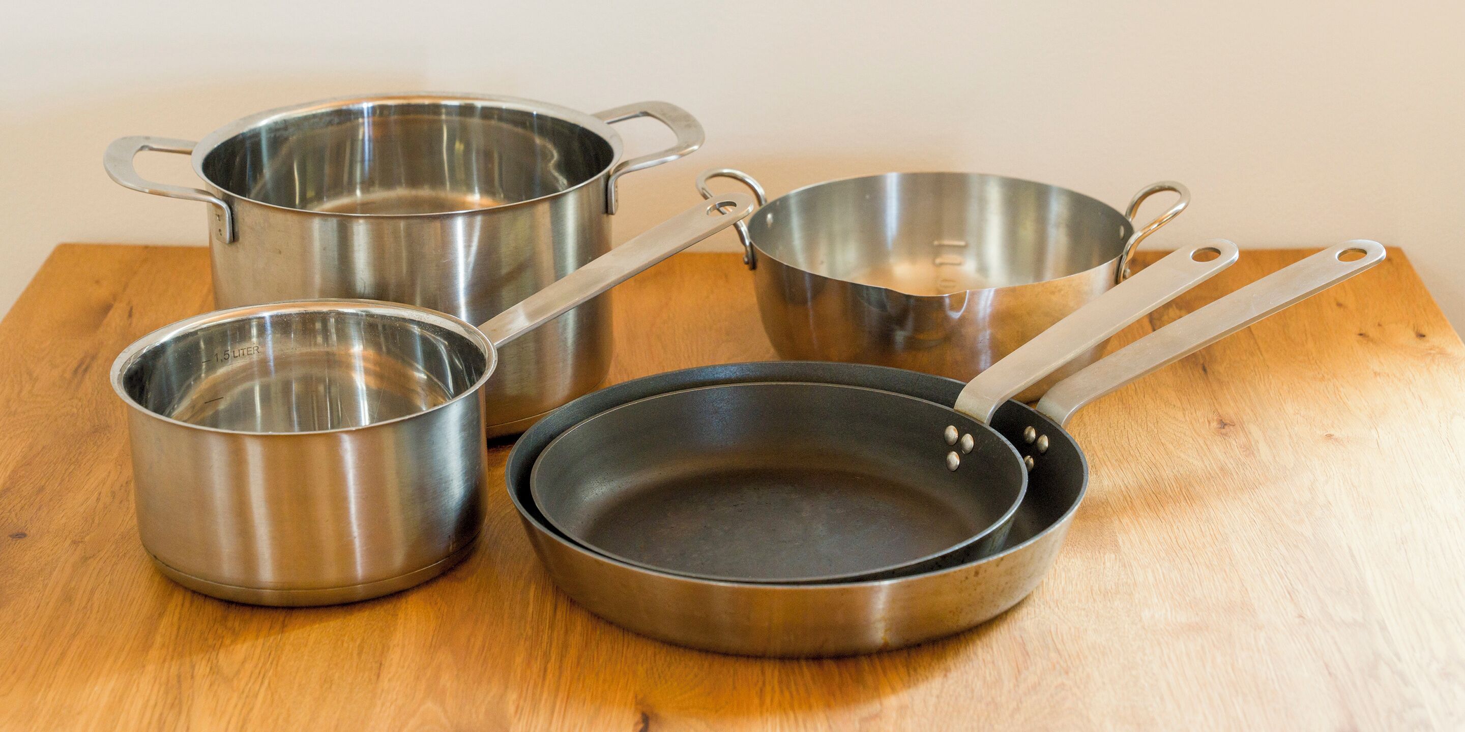 Cuatro utensilios de cocina de acero inoxidable sobre una superficie de madera.