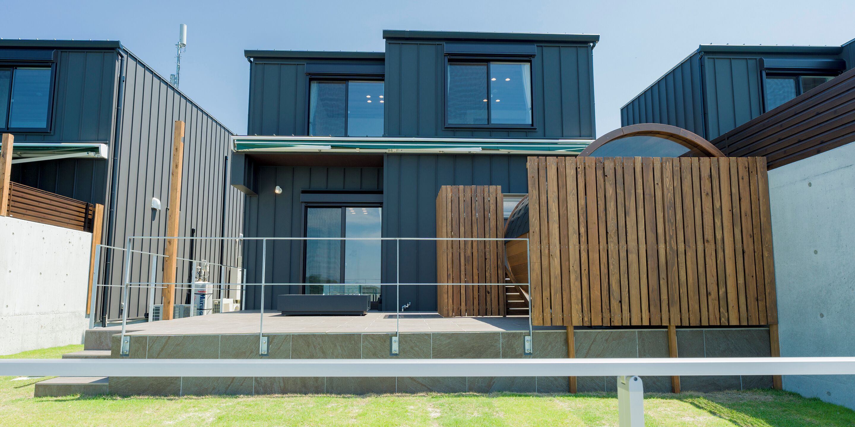 A modern building with multiple levels, large windows, and a covered outdoor area with a wooden fence.