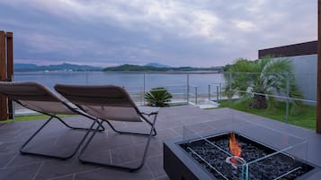 Una terraza con dos sillones, un pozo de fuego y vistas a un lago y montañas.