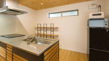 Una cocina compacta con horno empotrado, microondas y un lavabo con grifo de acero inoxidable.