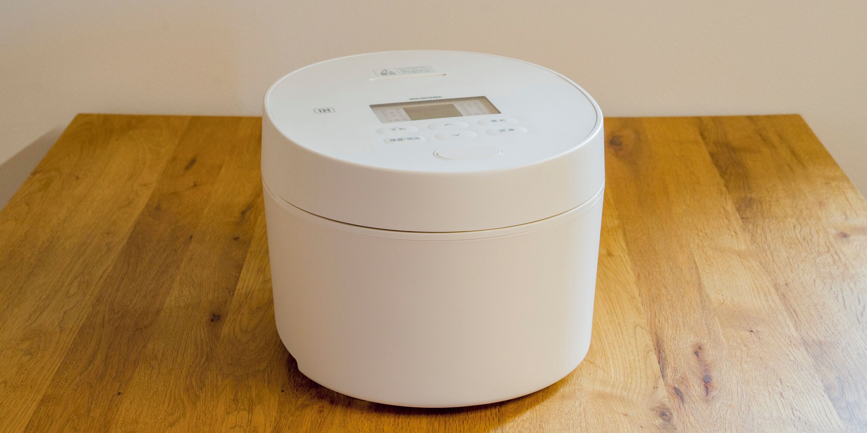 A white cylindrical device with a digital display on top, placed on a wooden table.