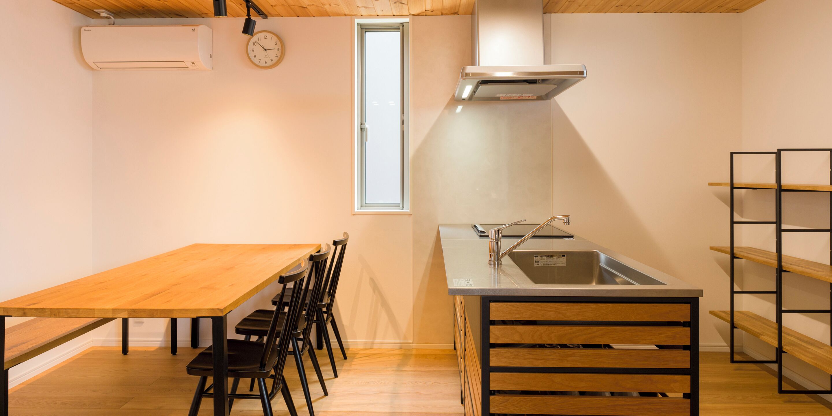 Una cocina compacta con una mesa y sillas de madera, un lavamanos empotrado y un ventanal.
