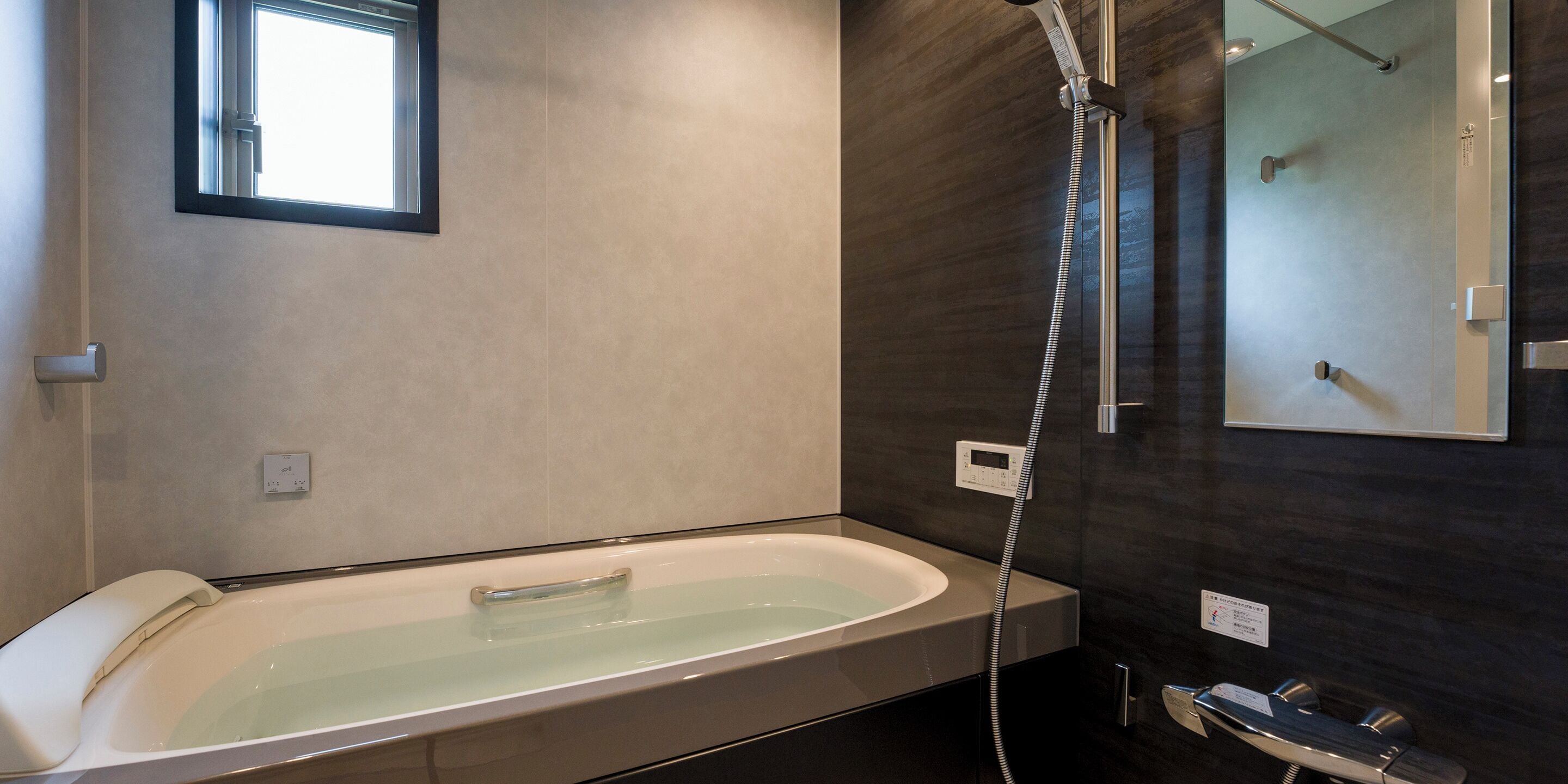 A modern bathroom with a freestanding bathtub, a handheld showerhead, and a wall-mounted mirror.