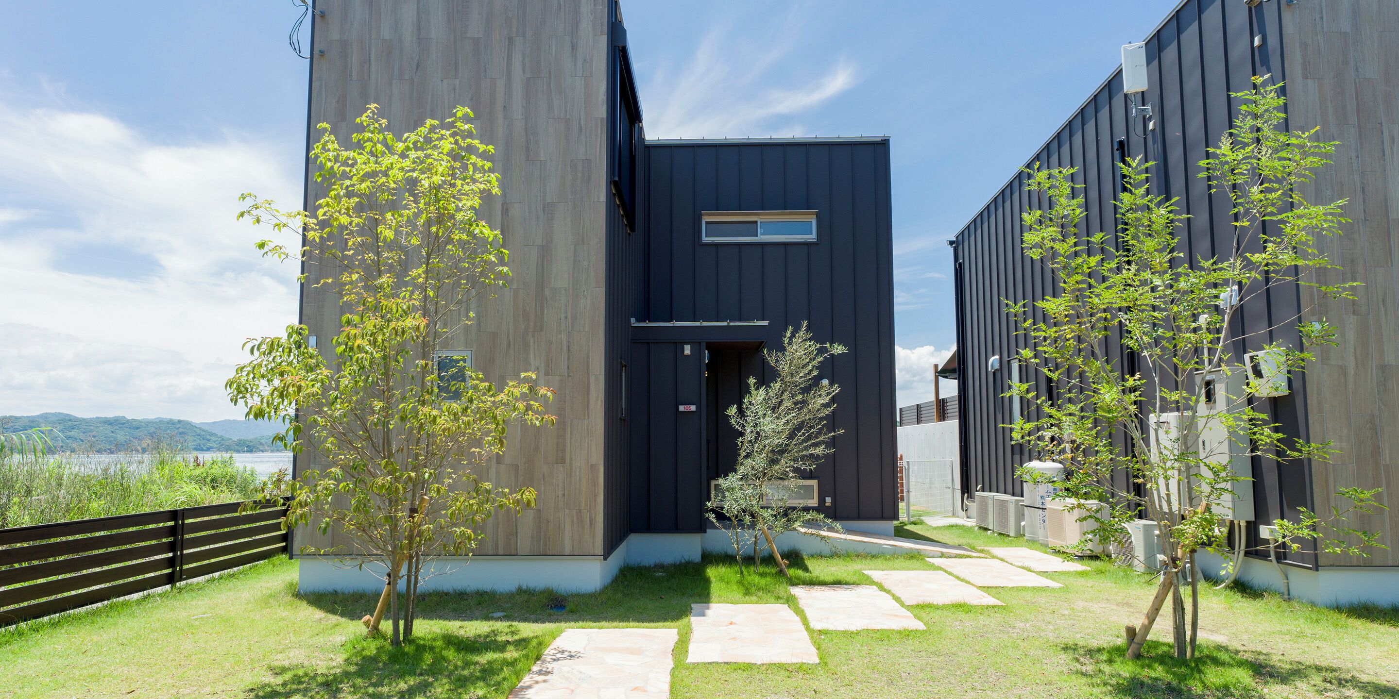 A modern building with a dark facade, a wooden fence, and a clear sky.