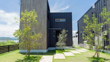 A modern building with a dark facade, a wooden fence, and a clear sky.