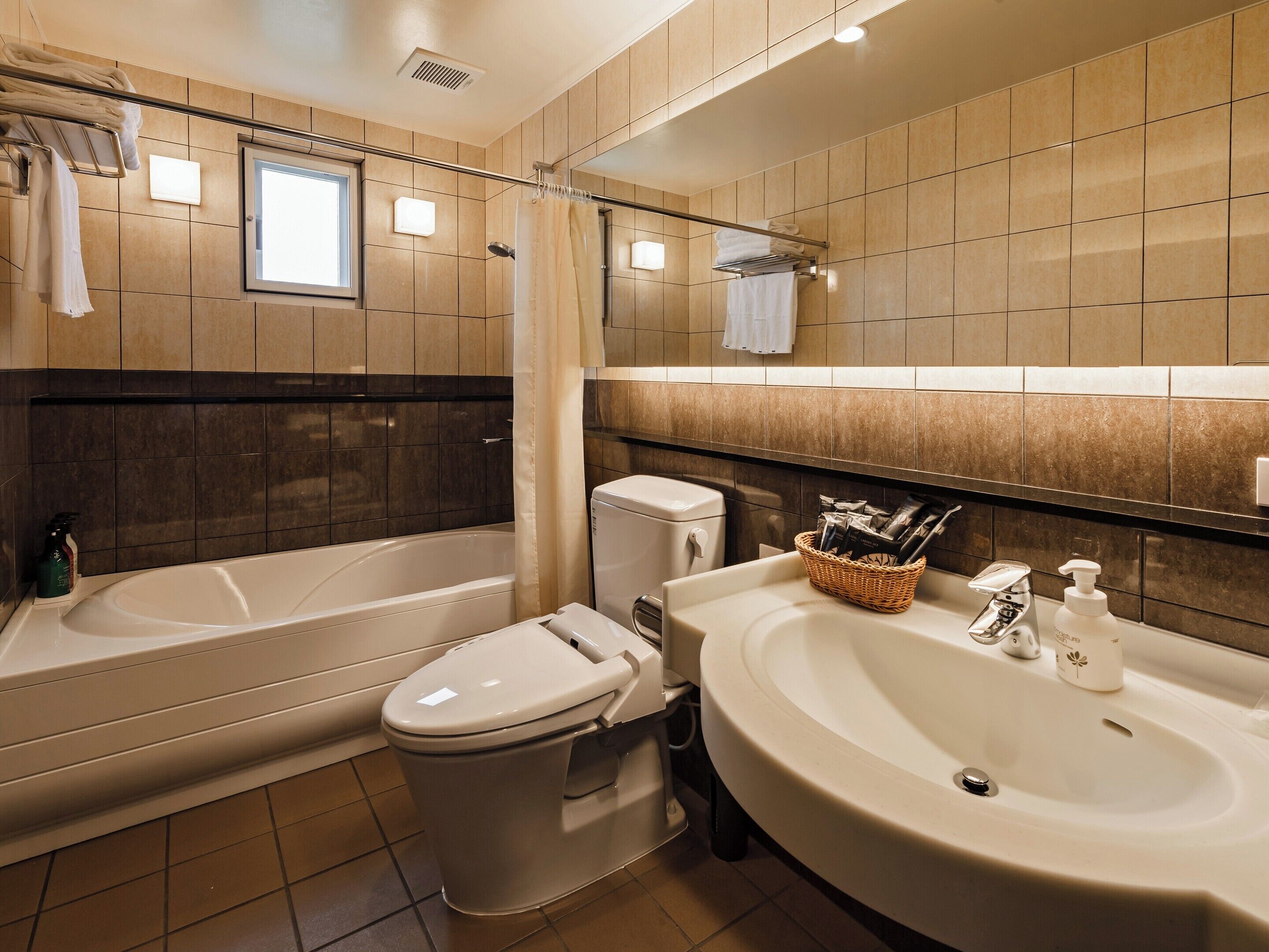 A bathroom with a bathtub, toilet, sink, and a mirror.