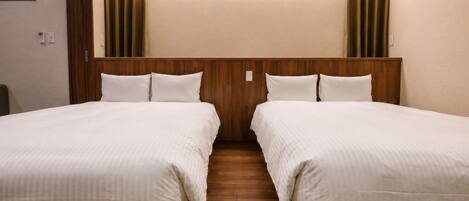 Habitación de hotel con dos camas, cabecero de madera y piso de madera.