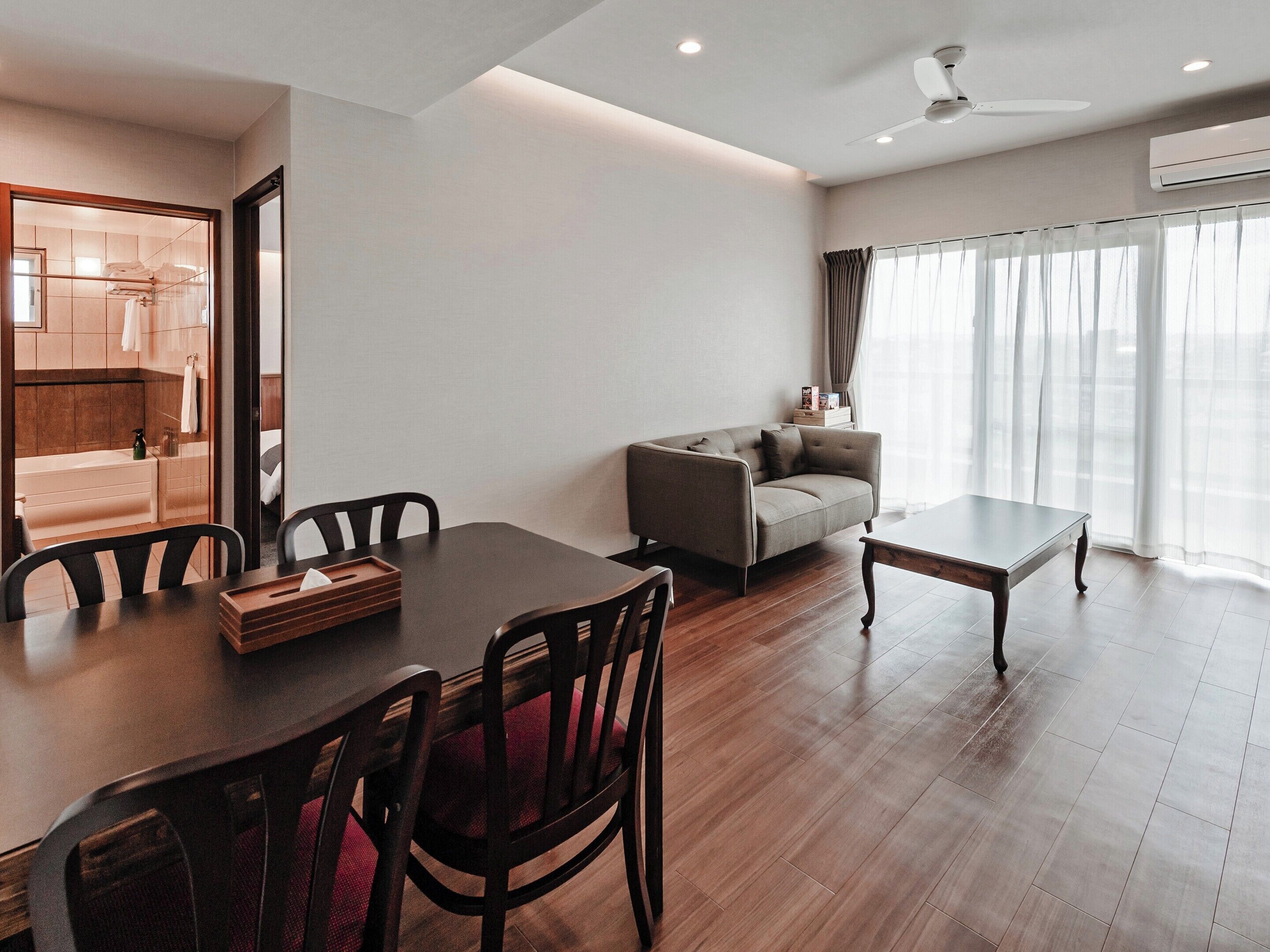 Una sala moderna con una mesa de comedor, sofá y vista al baño.
