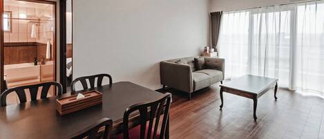 Una sala moderna con una mesa de comedor, sofá y vista al baño.