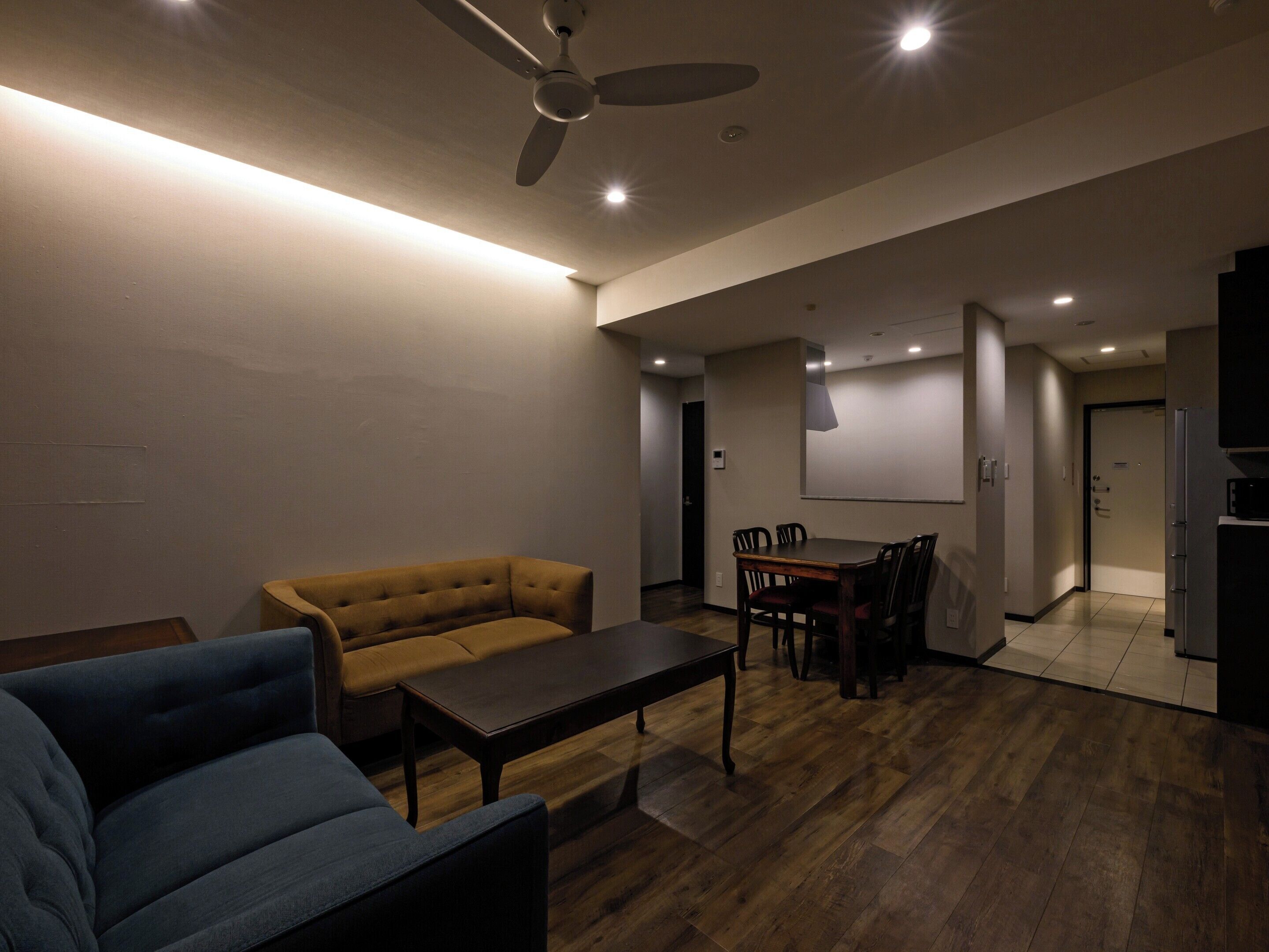 A modern living room with a sofa, a coffee table, and a dining area with chairs and a table.