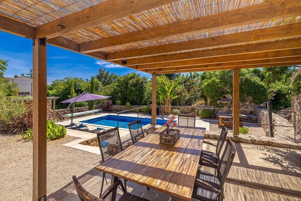 A covered outdoor area with a pool, wooden deck, and seating. - Beautiful Villa MAY with swimming pool (Gostinjac)
