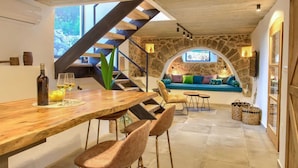 Un intérieur chaleureux avec une table à manger en bois, des chaises, un mur en pierre et un canapé bleu.