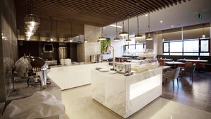 Una cocina moderna con una isla de mármol, electrodomésticos de acero inoxidable e iluminación colgante.