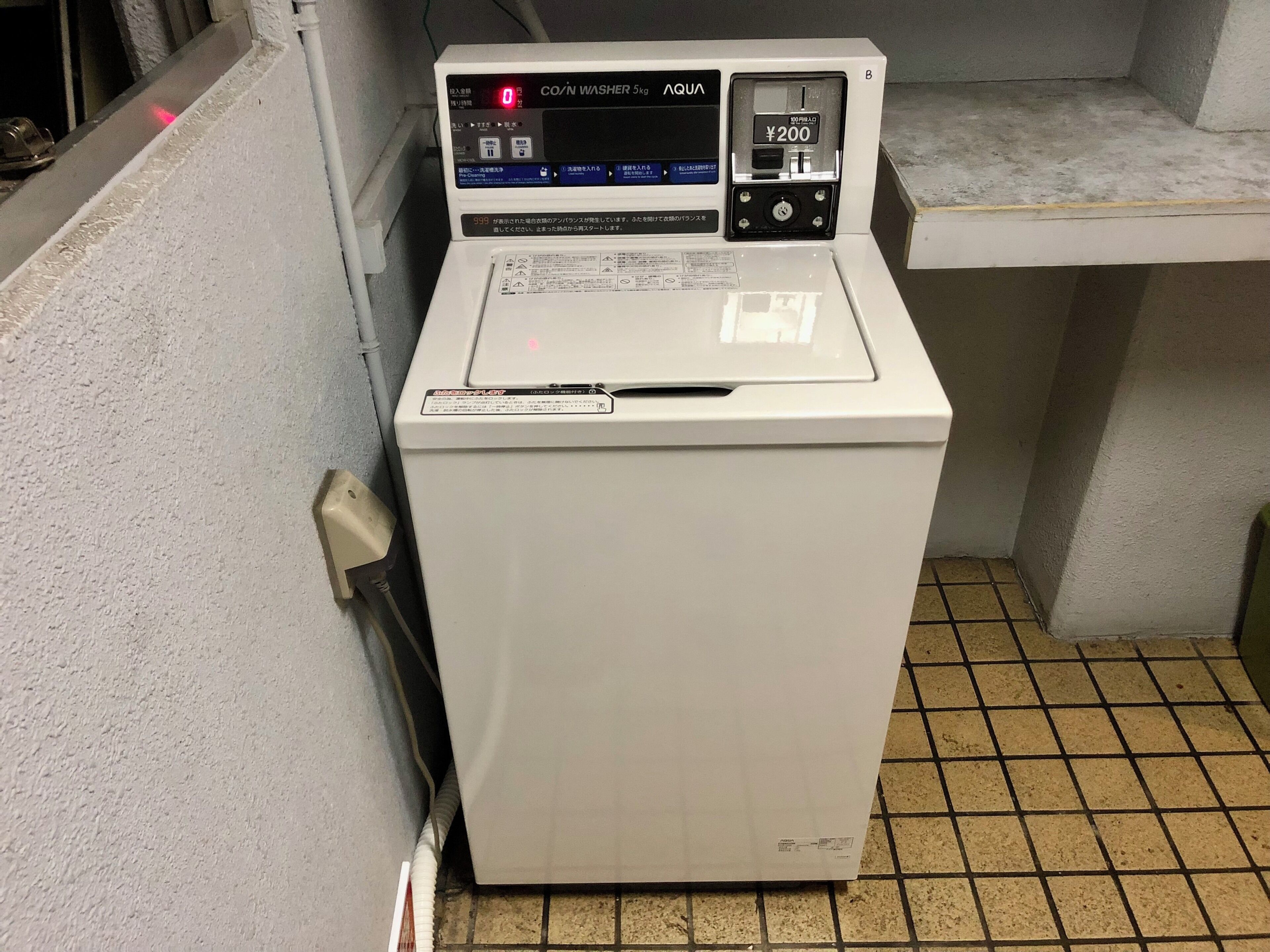 Una lavatrice CO/N bianca e compatta con display digitale e un prezzo di ¥200.
