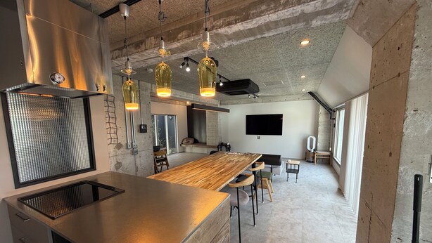 A modern kitchen with a large island, pendant lights, and a flat-screen TV. - Guest House Matsu Bekkan (Osaka)