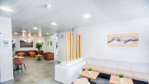Un espace d’accueil moderne comprenant un coin salon, une horloge et une œuvre d’art accrochée au mur.