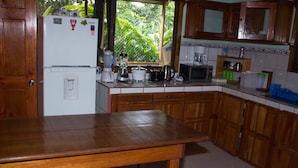 A kitchen with wooden cabinets, a white refrigerator, a wooden table, and various appliances.