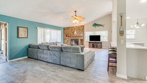 A spacious living room with a large gray sectional sofa, a stone fireplace, and a ceiling fan. - Private Dock: Riverfront Homosassa Home! (Homosassa)