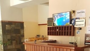 A reception desk with a flat-screen TV, a WiFi sign, and a sign indicating a hotel. - Moustakis Hotel (Kefalonia)