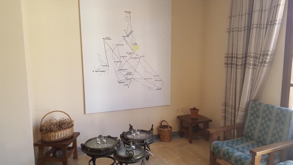 A living room with a large map on the wall, a blue patterned chair, a small wooden table, and a wicker basket.