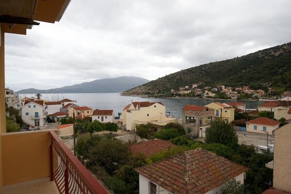 A coastal town with buildings along the waterfront, a view of the sea, and a hilly backdrop.