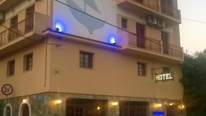 A hotel with a large sign on the facade, multiple balconies, and a stone base. - Moustakis Hotel (Kefalonia)