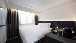 A hotel room with a large bed, a bedside table with a coffee maker, and a TV on the left side. - Moyen Hotel (Sokcho)