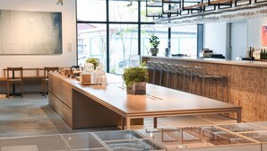 Una zona de bar moderna con una barra larga, asientos y una vitrina de vidrio.