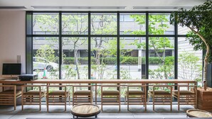 Una habitación con un gran ventanal, muebles de madera y una planta.